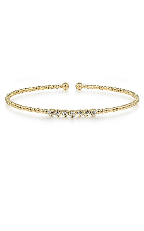 Gold bangle bracelet with a row of round diamonds set in a textured beaded band.