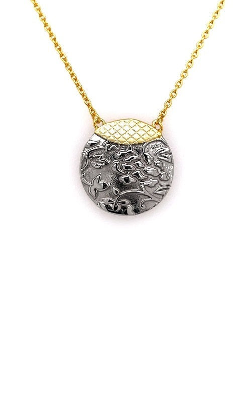 Round pendant with textured floral design in silver, accented with a gold-plated top section.