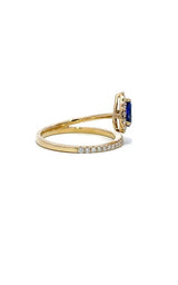 Gold ring with a split shank design, featuring a cushion-cut sapphire surrounded by a halo of smaller diamonds.